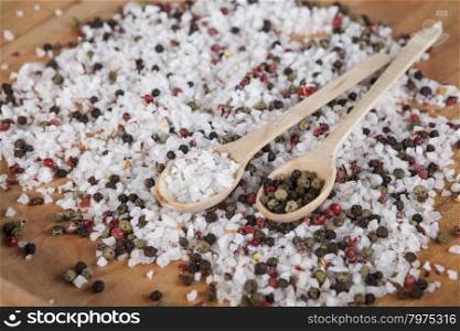 Large sea salt with red and black pepper. Large sea salt with red and black pepper in a wooden jar with a small wooden spoons on a beautiful wooden tray .