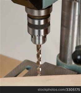 Large sized drill in solid chuck about to drill wood