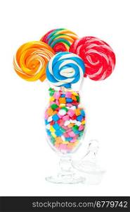 Large swirled lollipops displayed in an apothecary jar full of bubble gum. Shot on white background.