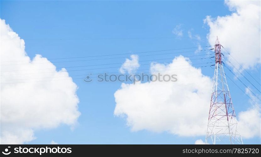 Large transmission towers located beside the river. Behind the clouds and the sky.