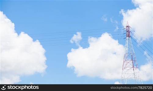 Large transmission towers located beside the river. Behind the clouds and the sky.