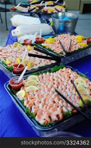 Large trays of shelled and cooked shrimp with lemon slices and seafood sauce.. Shrimp And Lemon Wedges