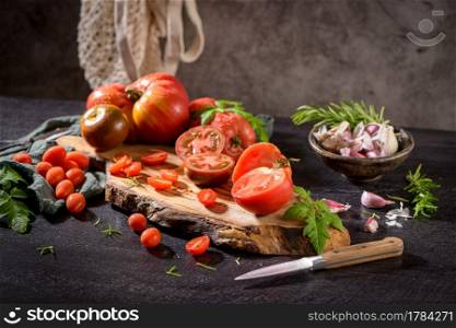 Large variety of tomatoes on rustic kitchen counter. Preparation of tomato sauce.