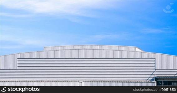 Large white aluminium industrial factory building with dome roof in modern style against blue sky background in panoramic view