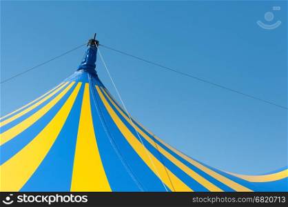 large yellow and blue circus big top canvas against a clear blue sky