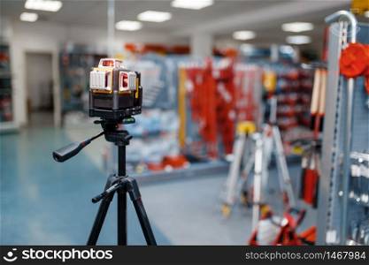 Laser level on tripod in tool store, nobody. Choice of measuring equipment in hardware shop, professional measure instrument in supermarket. Laser level on tripod in tool store, nobody