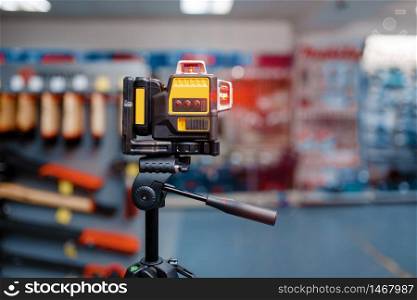 Laser level on tripod in tool store, nobody. Choice of measuring equipment in hardware shop, professional measure instrument in supermarket. Laser level on tripod in tool store, nobody