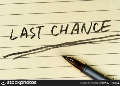 Last chance words written on lined paper with a pen on it