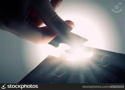 Last element of jigsaw. Hand connecting missing jigsaw glowing puzzle piece