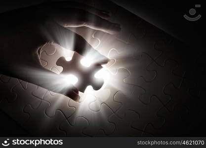 Last element of jigsaw. Hand connecting missing jigsaw glowing puzzle piece