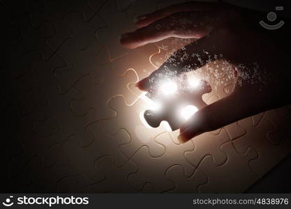 Last element of jigsaw. Hand connecting missing jigsaw glowing puzzle piece