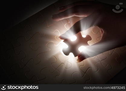 Last element of jigsaw. Hand connecting missing jigsaw glowing puzzle piece