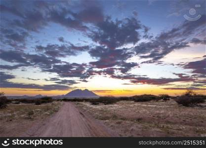 Last rays of sunlight color the clouds red after sunset Sptizkoppe Namibia