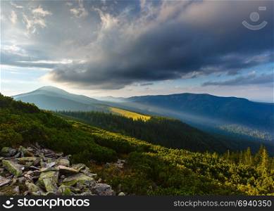 Last sun rays in evening sky with clouds above Syniak mountain. Summer sunset view from Homiak mountain, Gorgany, Carpathian, Ukraine.