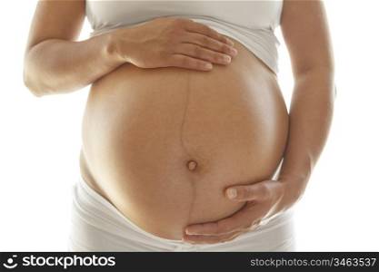 Last trimester pregnant woman holding her belly over a white background.