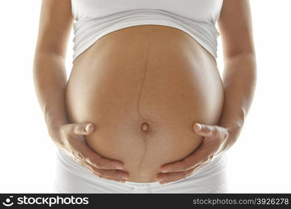 Last trimester pregnant woman holding her belly over a white background.