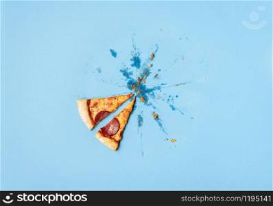 Lat two pizza pepperoni slices and grease traces, crumbs on blue background. Pizza salami leftovers and just two pieces. Eating pizza concept.