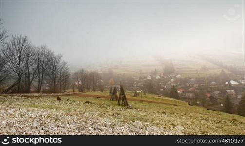 Late autumn misty morning in a village. First Snow in mountains