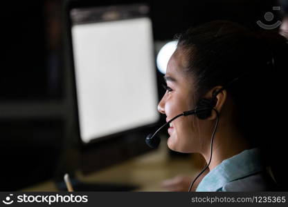 Late Night Environment. Side view young adult friendly Call centre operator with headsets working hard at night. Using for 24 Hr. 7 days Call center Concept.