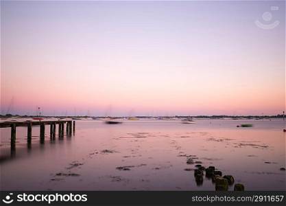Late Summer evening landscape image across calm port with blue sky and reflections in water