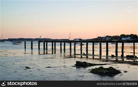 Late Summer evening landscape image across calm port with blue sky and reflections in water