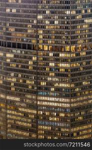 Late Working urban concept, window facade of business center office building at night, New York city NY USA