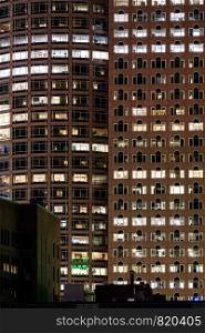 Late Working urban concept, window facade of business center office building at night, Boston, MA, USA.