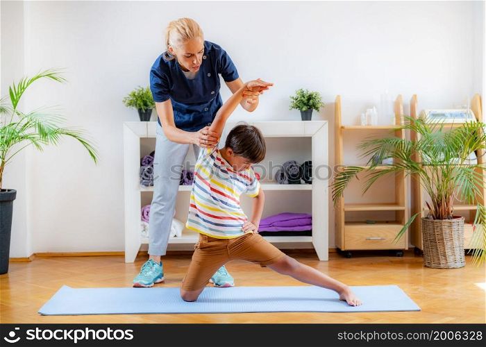 Lateral flexion exercise for children. Boy exercising with physical therapist.. Lateral flexion exercise for children.