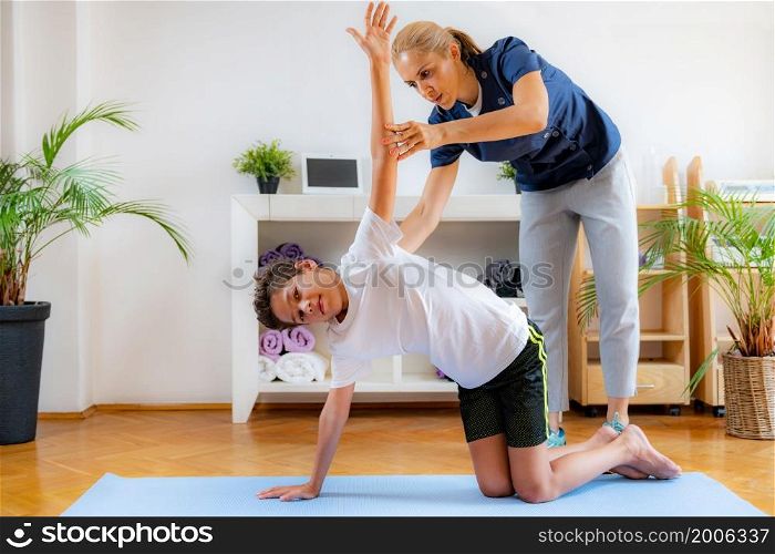 Lateral flexion exercise for children. Boy exercising with physical therapist.. Lateral flexion exercise for children.