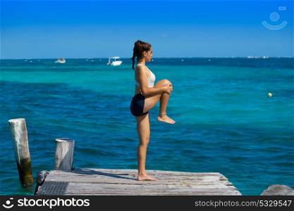 Latin athlete woman stretching in Caribbean beach pier