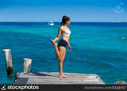 Latin athlete woman stretching in Caribbean beach pier