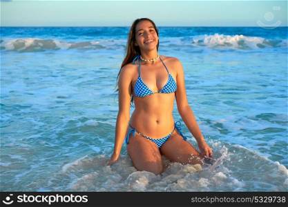 Latin beautiful bikini girl happy sitting in Caribbean beach sunset