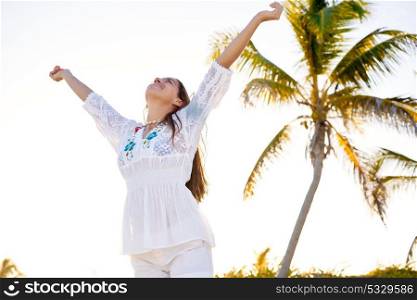 Latin beautiful girl happy open arms in Caribbean beach sand sitting relaxed