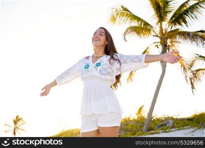 Latin beautiful girl happy open arms in Caribbean beach sand sitting relaxed