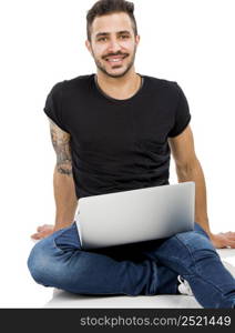Latin man sitting on the floor and working with a laptop