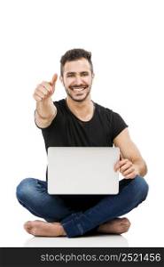 Latin man sitting on the floor and working with a laptop with thumbs up