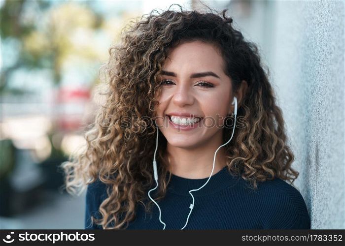 Latin woman smiling and looking at the camera while standing outdoors on the street. Urban concept.