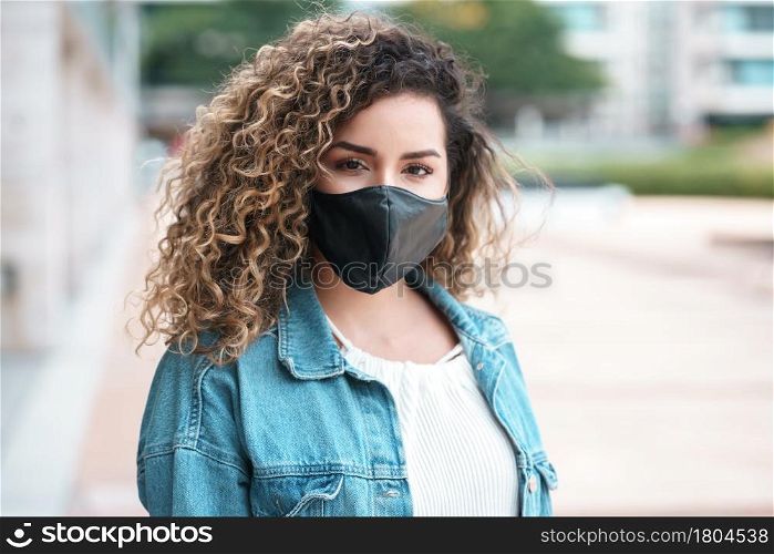 Latin woman wearing a face mask while standing outdoors on the street. Urban concept. New normal lifestyle concept.