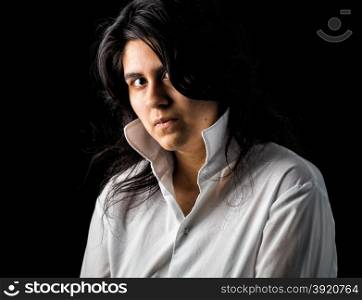 Latina teen in white shirt standing in front of black backdrop and looking at the camera. Latina teen in white on black backdrop