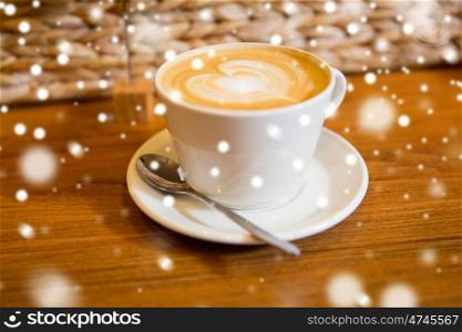 latte art, drink , love, christmas and valentines day concept - close up of coffee cup with heart shape drawing on cream froth over snow