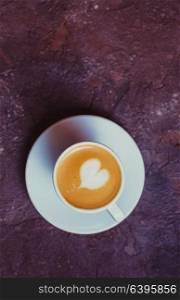 Latte art heart in cup of cappuccino. Top view on brown concrete background. Latte art heart