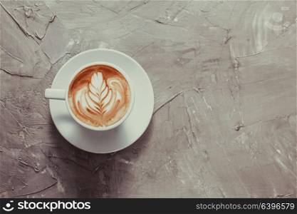 Latte art in cup of cappuccino. Top view on gray concrete background. Cup of cappuccino