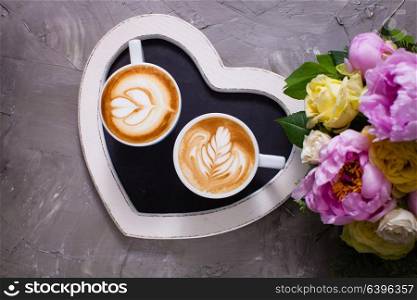 Latte art in two cups of cappuccino on the heart shape tray. Happy morning Valentine day couple. Love couple of cappuccino