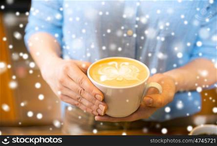 latte art, people and winter concept - close up of hands with butterfly etching in coffee cup over snow