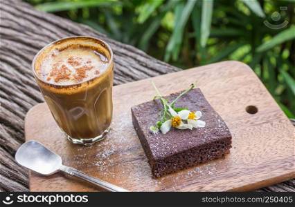 Latte Coffee and Chocolate Brownie Cake on Cutting Board on Wood Table on Tree Background. Latte coffee break time for food and drink category