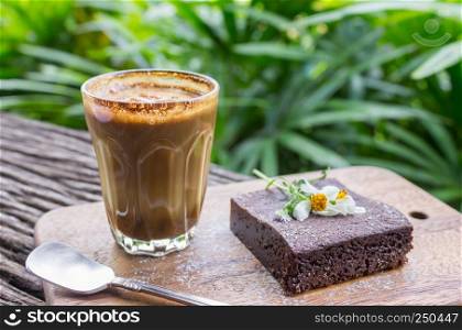 Latte Coffee and Chocolate Brownie Cake on Cutting Board on Wood Table on Tree Background. Latte coffee break time for food and drink category