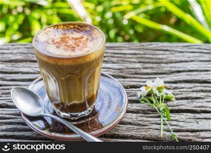 Latte Coffee and Daisy Flower and Spoon on Wood Table on Green Tree Background Left Zoom. Relax coffee break time in coffee shop on left frame