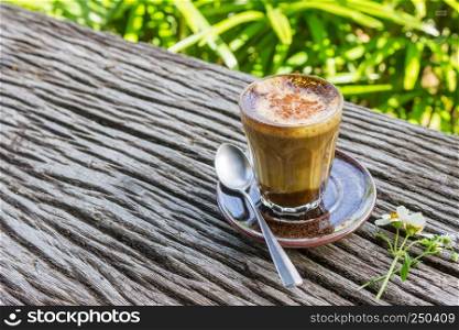Latte Coffee and Daisy Flower and Spoon on Wood Table on Green Tree Background Right. Relax coffee break time in coffee shop on left frame