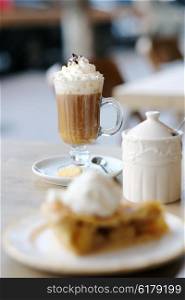 Latte with whipped cream and apple pie in outdoor restaurant