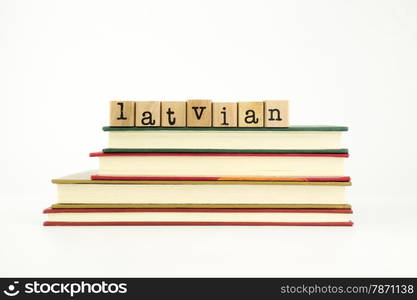 latvian word on wood stamps stack on books, foreign language and translation concept